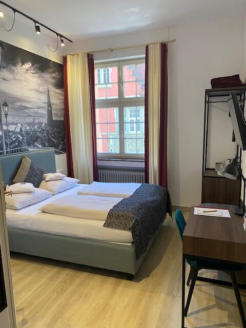 Doppelbett, daneben schönes Fenster mit  Gardinen 